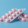 Magensaftresistente-Tabletten: Rosa Tabletten auf blauem Hintergrund