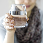 Frau hält Glas mit Wasser in die Kamera